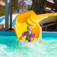 weinig meisje Aan water glijbaan Bij waterpark gedurende zomer vakantie foto