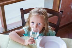 aanbiddelijk weinig meisje hebben ontbijt Bij restaurant foto