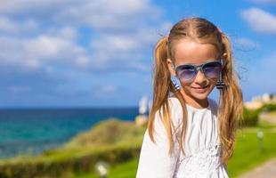 aanbiddelijk weinig meisje gedurende zomer vakantie buitenshuis foto