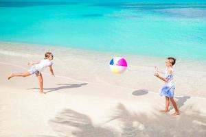 weinig aanbiddelijk meisjes spelen met bal Aan de strand foto
