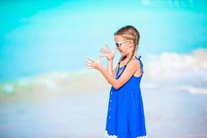 schattig weinig meisje in jurk Bij strand hebben plezier. grappig meisje genieten zomer vakantie. foto