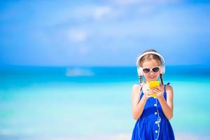 weinig meisje luisteren naar muziek- Aan hoofdtelefoons Aan de strand foto