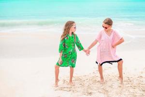 weinig meisjes hebben pret Bij tropisch strand spelen samen foto