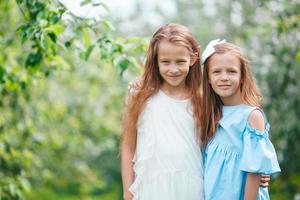 aanbiddelijk weinig meisjes in bloeiend appel boom tuin Aan voorjaar dag foto