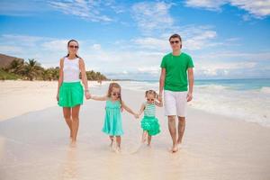 jong mooi familie van vier genoten ontspannende Aan de strand foto