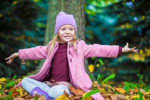 weinig aanbiddelijk meisje in herfst park Aan zonnig vallen dag foto