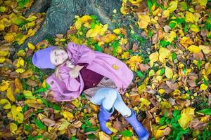 weinig aanbiddelijk meisje in herfst park Aan zonnig vallen dag foto