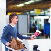 jong Mens met paspoorten en instappen passeert Bij de voorkant bureau in luchthaven foto