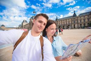 gelukkig jong familie met kaart van stad nemen selfie in Parijs foto
