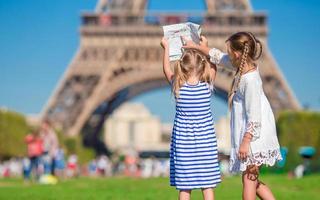 aanbiddelijk weinig meisjes met kaart van Parijs achtergrond de eiffel toren foto