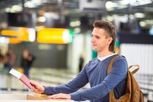 jong Mens met paspoorten en instappen passeert Bij de voorkant bureau in luchthaven foto