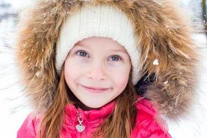 portret van weinig aanbiddelijk meisje in sneeuw zonnig winter dag foto
