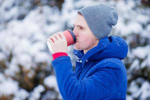 jong Kaukasisch Mens drinken koffie in bevroren winter dag buitenshuis foto