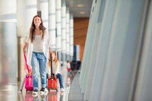 gelukkig familie met twee kinderen in luchthaven hebben pret aan het wachten voor instappen foto