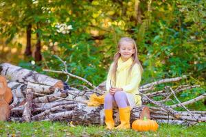 aanbiddelijk weinig meisje met een pompoen voor halloween buitenshuis Bij mooi herfst dag foto