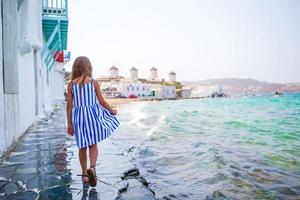 aanbiddelijk weinig meisje Bij weinig Venetië de meest populair toerist Oppervlakte Aan Mykonos eiland, Griekenland. mooi kind glimlach en kijken in de camera Aan weinig Venetië achtergrond. foto