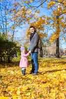 jong vader en weinig meisje genieten vakantie in herfst park foto