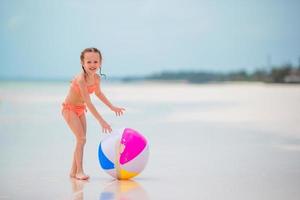 weinig meisje spelen met lucht bal Aan wit strand foto