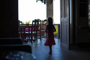 silhouet van jong meisje in een deuropening Bij groot donker huis foto