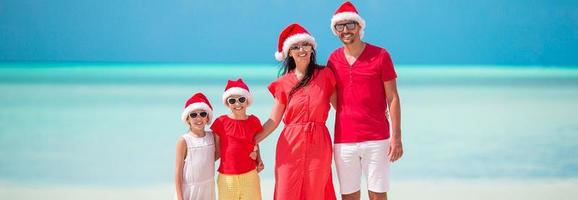gelukkig familie met twee kinderen in de kerstman hoed Aan zomer vakantie foto