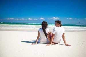 terug visie van jong paar in liefde zittend Bij tropisch wit strand foto