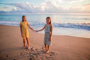 weinig gelukkig grappig meisjes hebben een veel van pret Bij tropisch strand spelen samen foto