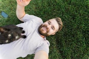 Mens met weinig katje aan het liegen en spelen Aan gras - vriendschap liefde dieren en huisdier eigenaar concept foto