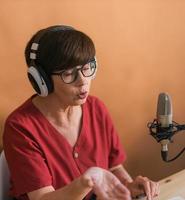 portret van volwassen vrouw vervelend hoofdtelefoons en pratend Bij online radio station - podcast en uitzending concept foto