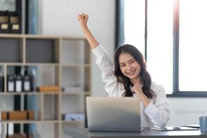 mooi Aziatisch vrouw gebruik makend van laptop computer, spannend en vieren met mooi zo nieuws van bedrijf succesvol. klein bedrijf opstarten concept. foto