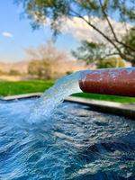 irrigatie water stromen van pijp naar kanaal voor landbouw velden foto