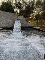 irrigatie water stromen van pijp naar kanaal voor landbouw velden foto