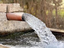 irrigatie water stromen van pijp naar kanaal voor landbouw velden foto