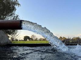 irrigatie water stromen van pijp naar kanaal voor landbouw velden foto