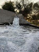 irrigatie water stromen van pijp naar kanaal voor landbouw velden foto