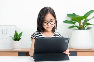 Aziatisch kind meisje leerling Wauw opgewonden Aan video telefoontje aan het leren naar aan het studeren online klasse of persoon leren van huis school- met tablet foto
