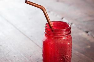 rode drank in een glas op een houten tafel foto