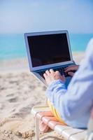 jonge man aan het werk op laptop op tropisch strand foto