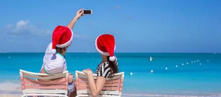 jong gelukkig paar in rood de kerstman hoeden nemen een foto