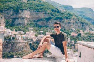 zomer vakantie in Italië. jong Mens in positano dorp Aan de achtergrond, amalfi kust, Italië foto