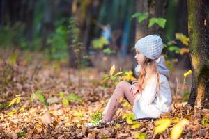 aanbiddelijk weinig meisje met herfst bladeren in de mooi park foto