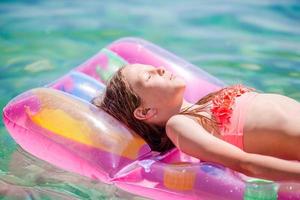 aanbiddelijk meisje Aan opblaasbaar lucht matras in de zee foto
