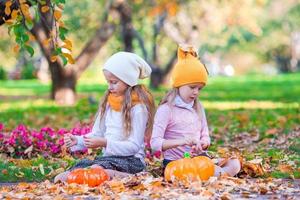 aanbiddelijk weinig meisjes met pompoenen buitenshuis Bij mooi herfst dag. truc of traktatie foto