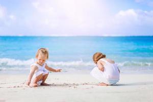 weinig gelukkig grappig meisjes hebben een veel van pret Bij tropisch strand spelen samen. foto