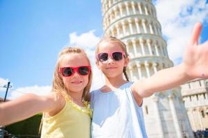 weinig kinderen nemen selfie achtergrond de leunend toren in pisa, Italië. foto over Europese vakantie