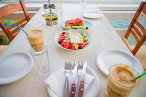 traditioneel lunch met heerlijk vers Grieks salade en brusketa geserveerd voor lunch Bij buitenshuis restaurant met mooi visie Aan de zee en haven foto