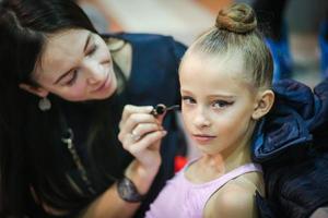 moeder maken omhoog naar haar dochter met cosmetica, bloost, oog schaduwen en borstels foto