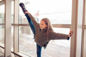 weinig meisje in luchthaven in de buurt groot venster terwijl wacht voor instappen foto