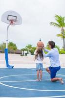 jong Mens en weinig meisje spelen basketbal buiten Bij exotisch toevlucht foto