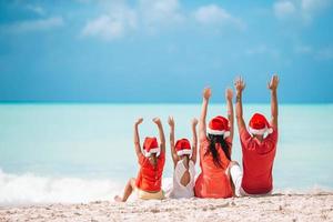 gelukkig familie met twee kinderen in de kerstman hoed Aan zomer vakantie foto