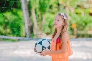 aanbiddelijk weinig meisje spelen met bal Aan strand. kinderen zomer sport buitenshuis Aan caraïben eiland foto